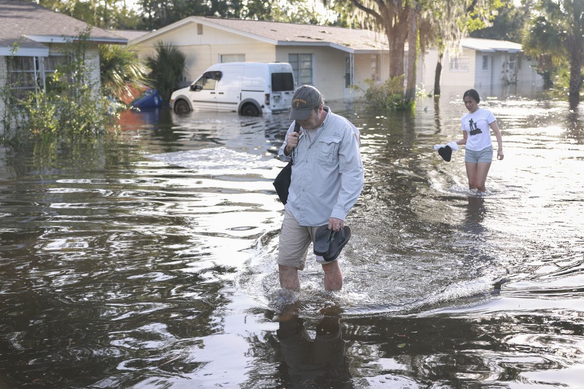 People walk through a flooded road after Hurricane Helene hit the area as it passed offshore on Friday in Crystal River, Fla.  (Joe Raedle)