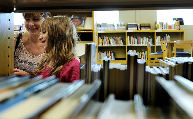 Ten-year-old Kaylee Martin and her mom Michele Martin browse the book selection at Liberty Lake Library on Tuesday. The library is celebrating its 10th anniversary this year. (Kathy Plonka)