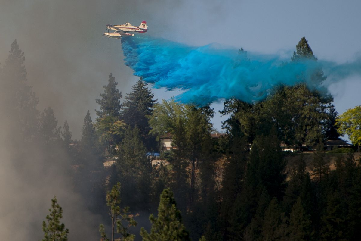 An air attack fire unit drops fire retardant on a brush fire on the slope below High Drive on July 28, 2014, in Spokane, Wash. (Tyler Tjomsland / The Spokesman-Review)