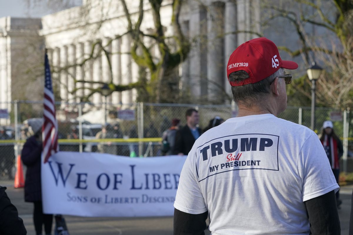 A supporter of President Donald Trump listens to speakers during a rally, Sunday, Jan. 10, 2021, at the Capitol in Olympia, Wash. Protesters from several causes rallied Sunday at the Capitol, which was secured with a perimeter fence and National Guard members, the day before the 2021 legislative session was scheduled to begin.  (Ted S. Warren)