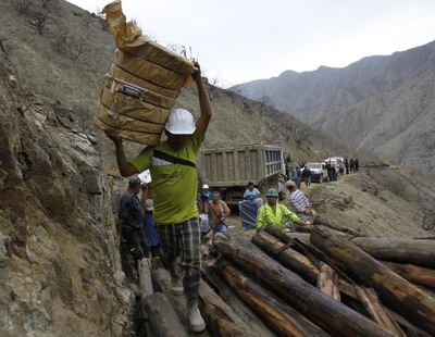 Welcome delivery: Men carry cooking pots Monday near the entrance of a wildcat mine in Yauca del Rosario, Peru, where nine miners have been trapped since Thursday. Peruvian authorities say the miners are being supplied with sports drinks, soup and food while emergency responders work to free them. (Associated Press)