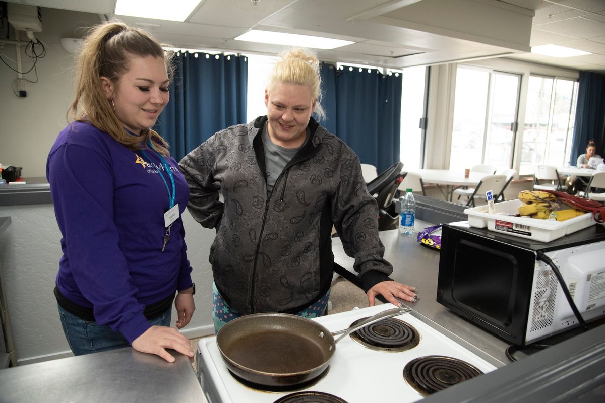 Supervisor Heather Baker stands with single mom Amber Warne in the communal kitchen area at the Family Promise shelter at 2002 E. Mission Ave. on Tuesday. The nonprofit provides shelter space to homeless families who cook, clean and sleep on the main floor of the former grocery store at East Mission Avenue and Napa Street.  (Jesse Tinsley/The Spokesman-Review)