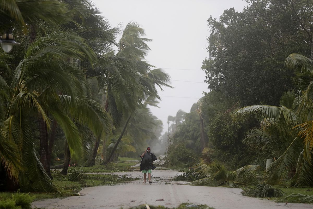 A person walks through a street lined with debris and fallen trees as Hurricane Irma passes through Naples, Fla., Sunday, Sept. 10, 2017. (David Goldman / Associated Press)