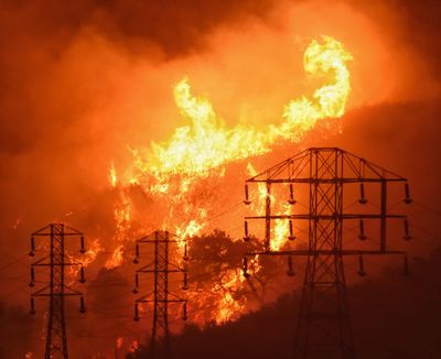 Flames burn near power lines Dec. 16, 2017, in this photo provided by the Sanda Barbara County Fire Department in Sycamore Canyon near West Mountain Drive in Montecito, Calif. (Mike Eliason / AP)