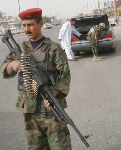 
An Iraqi army soldier stands guard as his colleague searches a car in Basra on Tuesday. Associated Press
 (Associated Press / The Spokesman-Review)