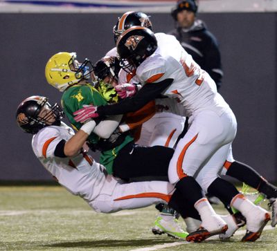 Tanner Pauly is taken down by a trio of Kennwick Lions during Shadle’s rout. (Jesse Tinsley)