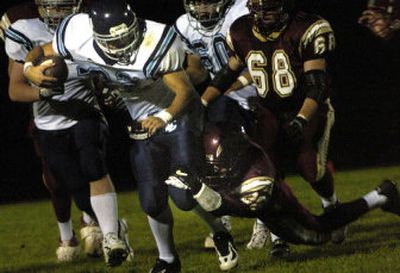 Kyle Ferebee of Lake City, in white, attempts to fend off a tackle from Eric Puyear during the Timberwolves' 29-9 non-league win at University on Wednesday night. 
 (Holly Pickett / The Spokesman-Review)