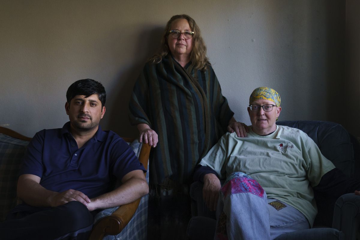 Ihsanullah Patan, left, a horticulturist and refugee from Afghanistan, sits for a portrait with Caroline Clarin, right, whom he worked with in Afghanistan, and her wife, Sheril Raymond, at his home in Fergus Falls, Minn., Friday, Oct. 29, 2021. A U.S. Department of Agriculture adviser in Afghanistan, Clarin along with her wife have been using their own time and money to get Afghans who worked for her program out of the country. Those who have started their life in the remote town of Fergus Falls near the North Dakota border say they consider them family.  (David Goldman)
