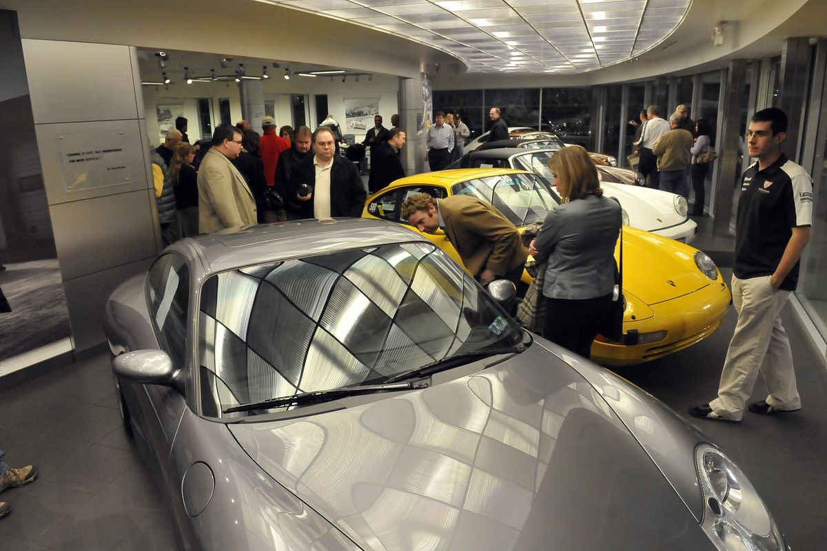 Party guests gather around the many recent and classic Porsche cars on display at the Porsche dealer in Liberty Lake on Saturday. In the foreground is Karch Polgar’s 2003 Carrera 4S. (Jesse Tinsley)