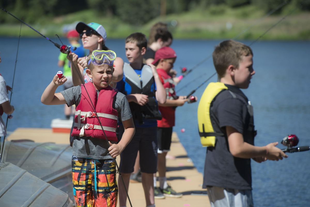 First-time camper, Drew Greger, 9, left, tries is hand at fishing, June 21, 2017, off the docks at Camp Reed. (Dan Pelle / The Spokesman-Review)