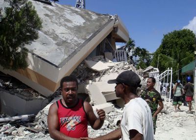 Residents stand in front of  a collapsed hotel after an earthquake in Manokwari, Indonesia, on Sunday.  (Associated Press / The Spokesman-Review)