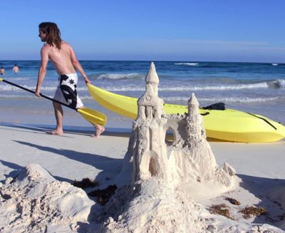 A man drags a kayak past a sand castle in Tulum, Mexico. (AP file photo)