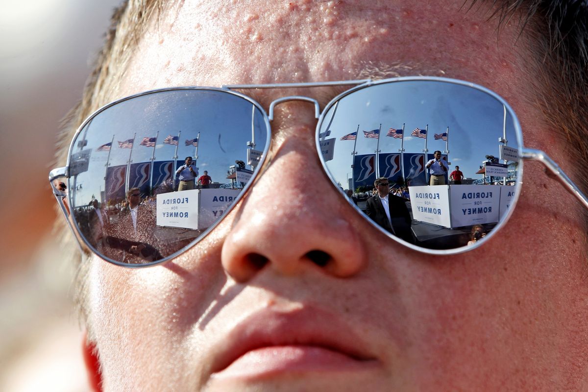 Republican presidential candidate, former Massachusetts Gov. Mitt Romney, left, and vice presidential candidate, Rep. Paul Ryan, R-Wis., are seen reflected in a supporters