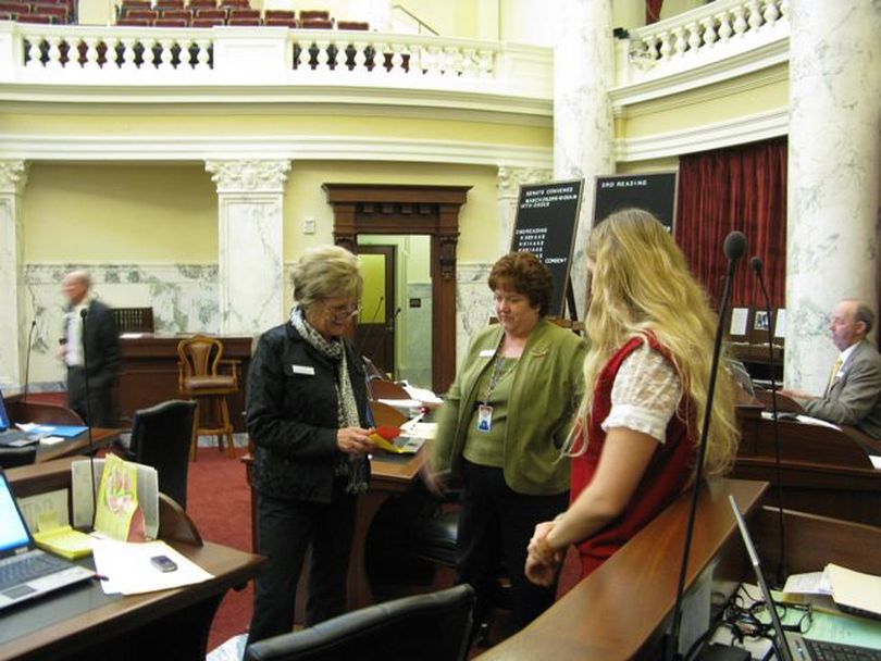 Sens. Diane Bilyeu, D-Pocatello, left, and Joyce Broadsword, R-Sagle, center, talk with a Senate page during a break in Senate proceedings late Monday. (Betsy Russell)
