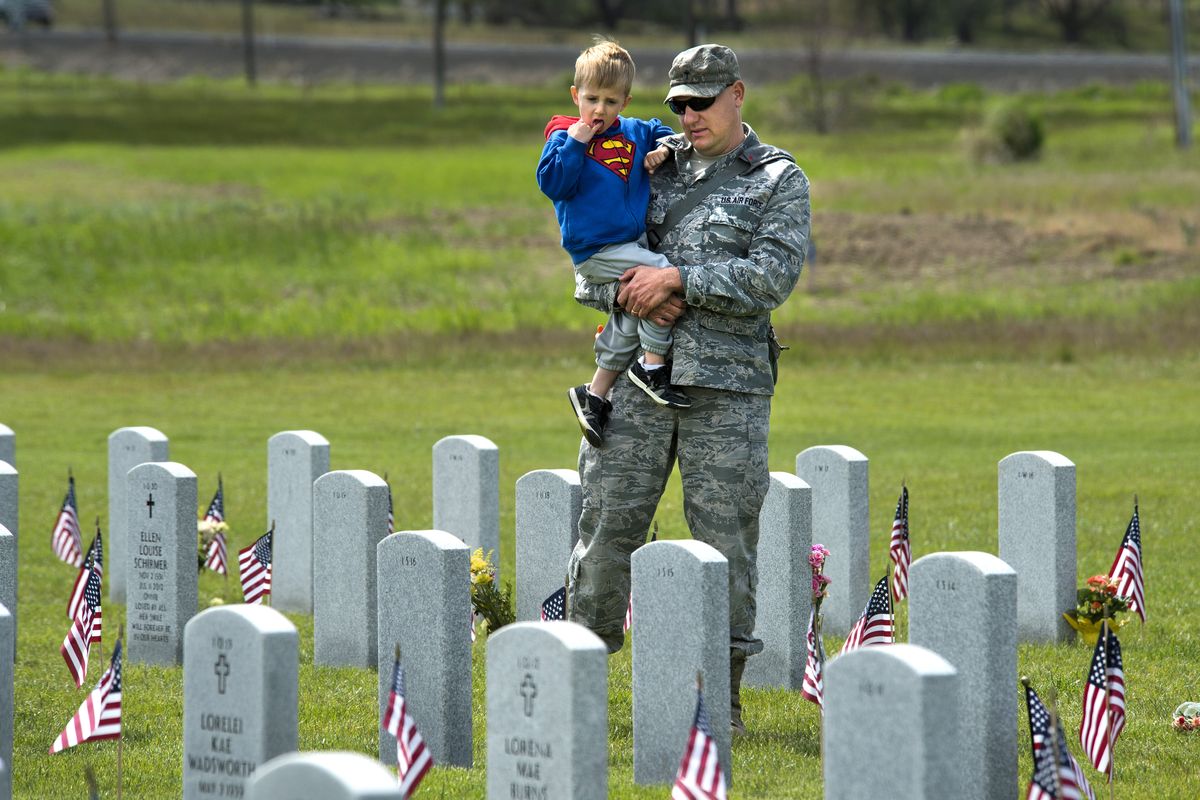 Air Force Chaplain Cpt. Jeremy Bastian talks with his son, Eli, 4, as the pair visit the graves of fallen soldiers Monday at the Washington State Veterans Cemetery in Medical Lake. “I wanted to say thank you to those who gave their life,” Bastian said. (Dan Pelle)