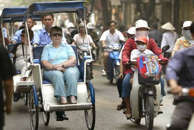 
Foreigners tour a busy street of Hanoi, Vietnam, in a cyclo, three-wheeled taxi. Vietnam has undergone major changes since its war days.
 (Associated Press photos / The Spokesman-Review)