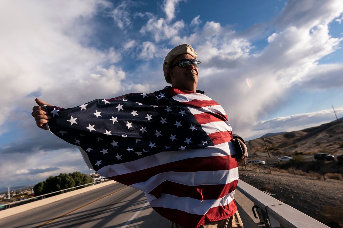 John Hiickman cheers on a convoy of truckers heading toward Washington to protest COVID-19 mandates Wednesday in Needles, Calif.  (Nathan Howard)