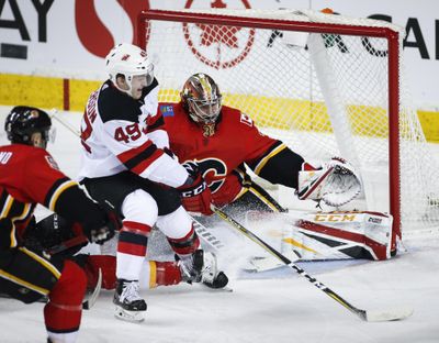New Jersey Devils' Joey Anderson, center, is knocked to the ice as he tries to score on Calgary Flames goalie David Rittich during the first period Tuesday, March 12, 2019, in Calgary, Alberta. Calgary won 9-4. (Jeff McIntosh / Associated Press)