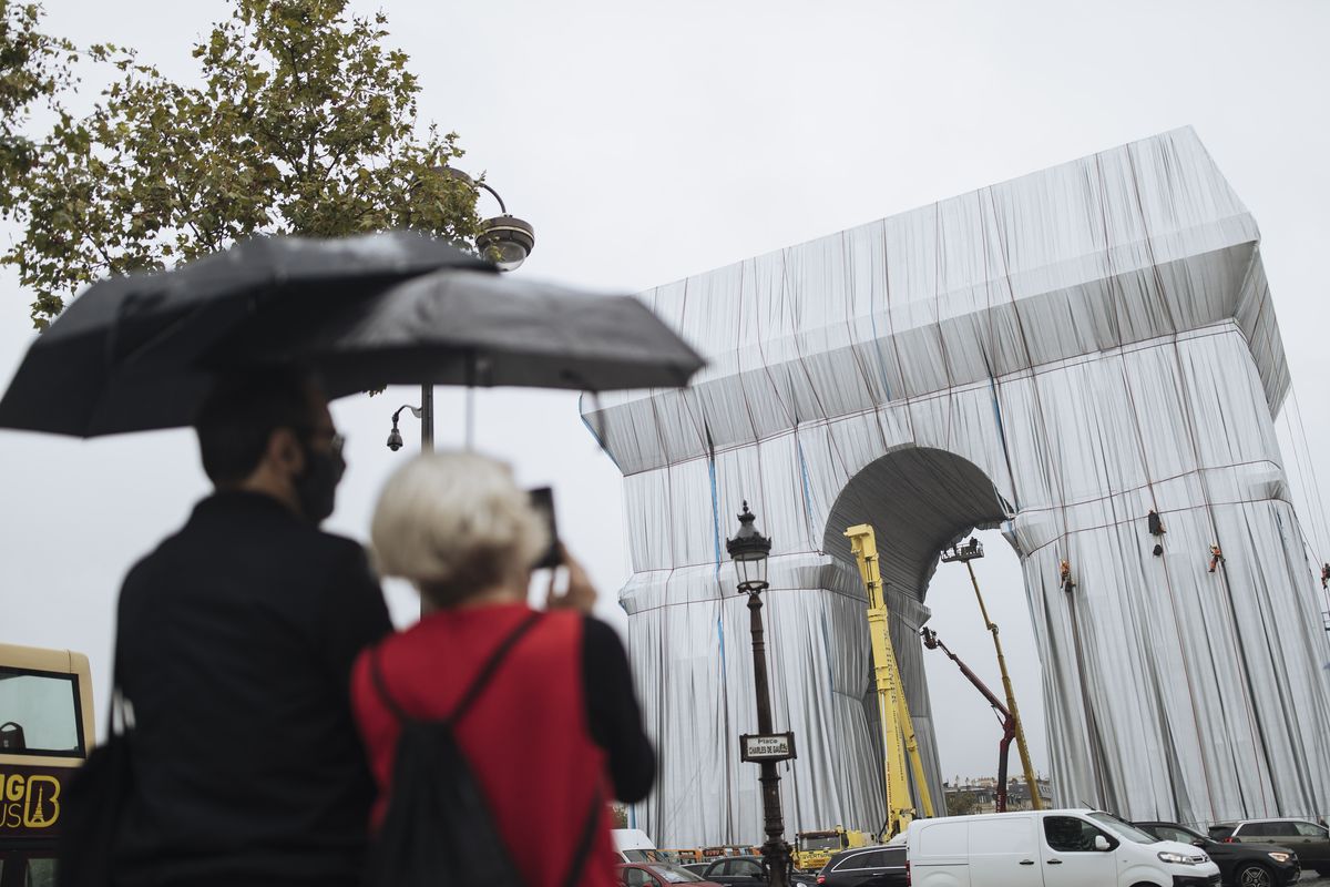 People watch workers wrapping the Arc de Triomphe monument Wednesday in Paris. The “L’Arc de Triomphe, Wrapped” project by late artist Christo and Jeanne-Claude will be on view until Oct. 3.  (Lewis Joly)