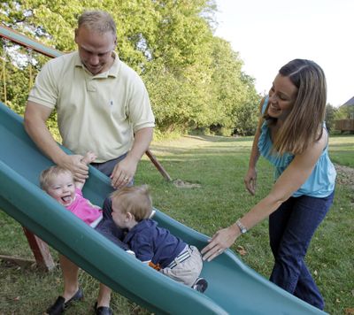 Corey and Lindsey Groepper play with their 1-year old twins, Riley and James, in Indianapolis on Tuesday. After the children were born, the couple pared back their entertainment spending to help save for their college funds.  (Associated Press)