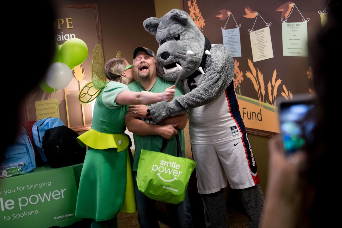 Rick Clark, a community activist and Gonzaga student who was formerly homeless, is embraced by Molli Corcoran, aka the Delta Dental Tooth Fairy, and Spike The Gonzaga Bulldog on Thursday, May 31, 2018, at at Second Harvest Food Bank in Spokane, Wash. Clark was honored for his community outreach work. (Tyler Tjomsland / The Spokesman-Review)