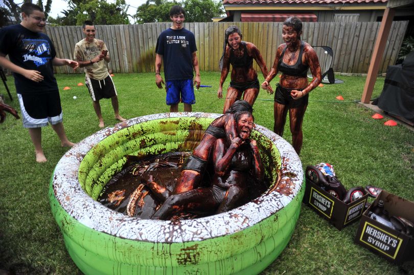 Catherine Jolley, 17, left, and Chelsea Leach, 18, both members of the Northeast High School girls volleyball team, wrestle in a wading tub full of Hershey's chocolate syrup, Friday, March 27, 2009 in one of the team member's backyard in Oakland Park, Fla. The girls team, egged on by the boys team, were just having fun to mark the end of the girls season and the start of the boys season. They used 27 bottles of the syrup. (Joe Cavaretta / The Spokesman-Review)