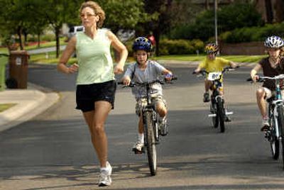 
Kellee Daugherty, 44, runs with her three children following on their bikes on Thursday in Spokane. 
 (Jed Conklin / The Spokesman-Review)