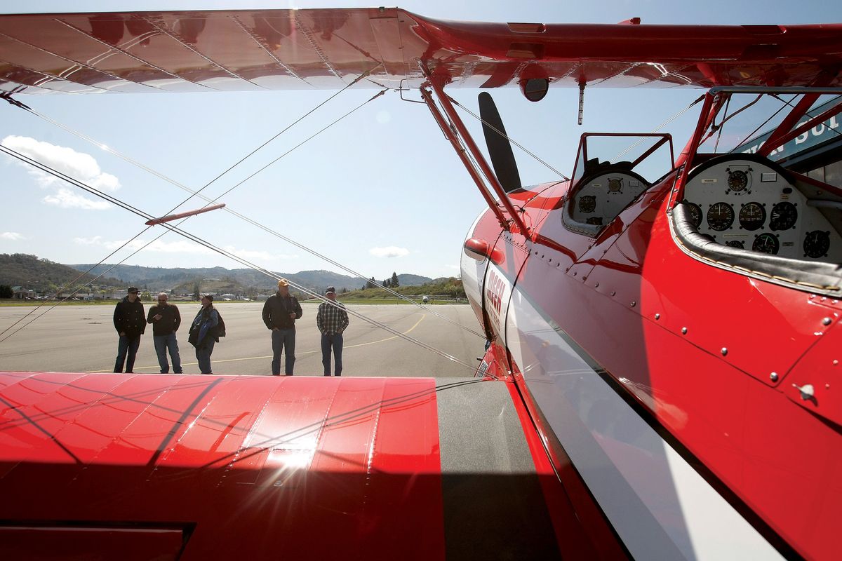Men gather at the Roseburg, Ore., airport to get a look at a 1943 Boeing Stearman biplane that its owners are using to give veterans free rides. (Associated Press)