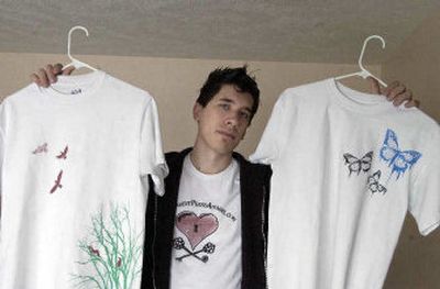 
Caleb Heale poses at his Newman Lake home with samples of his T-shirts that he silk-screens. 
 (J. BART RAYNIAK photos . / The Spokesman-Review)