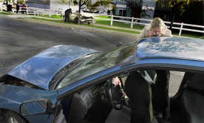 
Hanna Smart collects her belongings from her wrecked car at Providence and Cook on Monday morning. Police chased the driver of a 1980 Volare, background against tree, who caused multiple wrecks, including this and another at Empire Avenue and Pittsburg Street that flipped an SUV onto its side in a yard. 
 (Christopher Anderson/ / The Spokesman-Review)