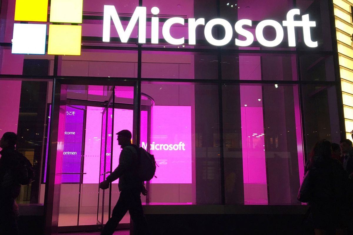 FILE - In this Nov. 10, 2016, file photo, people walk past a Microsoft office in New York. For the first time in two years for many people, the American workplace is transforming into something that resembles pre-pandemic days. The U.S. has since seen COVID-19 infections and hospitalizations plummet. Cases have plunged from 455,000 a day two weeks ago to 150,000 on Monday, Feb. 14, 2022. (Associated Press )