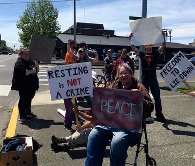 Local citizens protest the new ordinance that prohibits sitting on the sidewalk in downtown Aberdeen. For most of the past two days, Mike Nelson has been sitting on the sidewalk to protest what he says is an unconstitutional rule that unfairly targets homeless people. (Facebook)