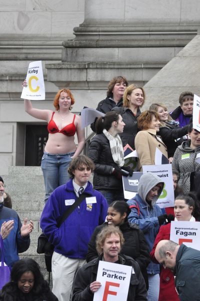 OLYMPIA -- Taylor Malone of Spokane joins protesters on the steps of the state Capitol calling for the Legislature to fund programs to help the poor. She said she took off her shirt to symbolize that with cuts to programs, some people have to make the choice between feeding their familes and buying them clothes (Jim Camden)