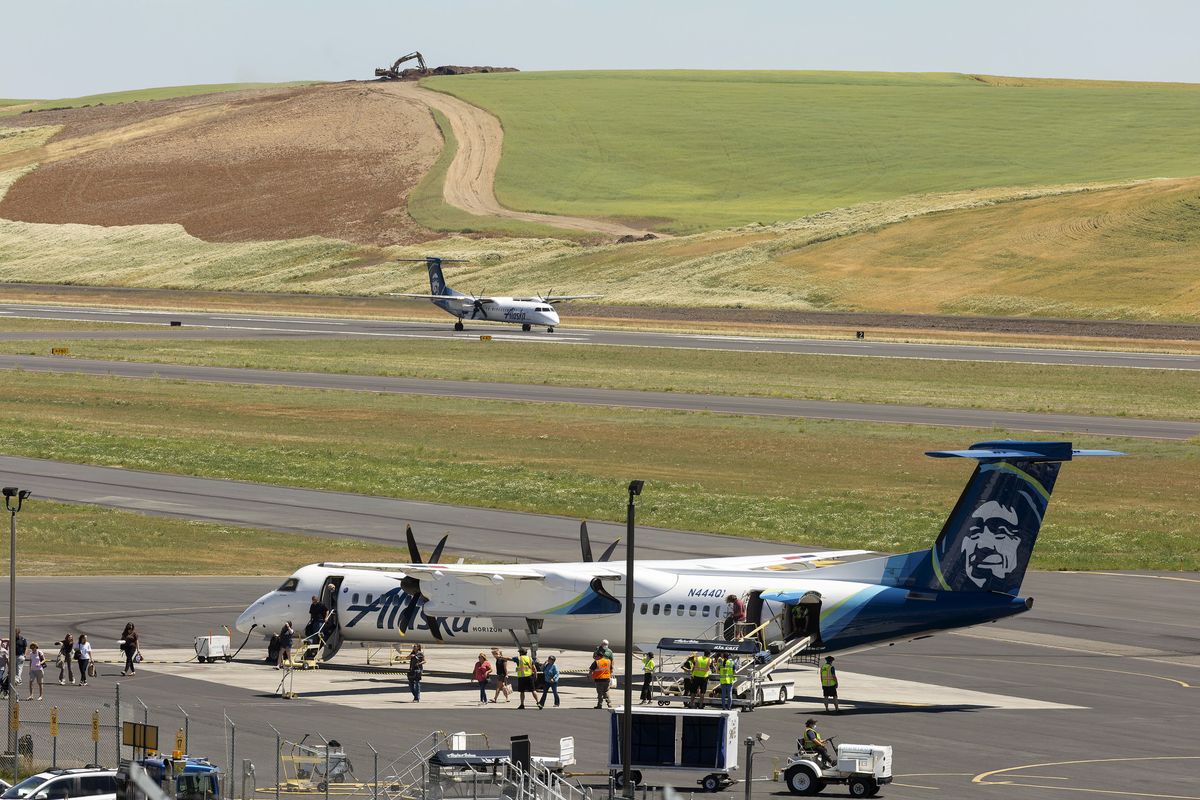 Passengers exit an Alaska Air airplane Thursday outside the terminal at the Pullman-Moscow Regional Airport while another flight takes off from the new runway.  (Geoff Crimmins/For The Spokesman-Review)