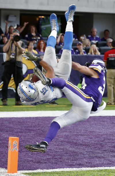 Detroit wide receiver Golden Tate flips into the end zone in front of Vikings strong safety Andrew Sendejo, right, to score on a 28-yard pass. (Jim Mone / Associated Press)