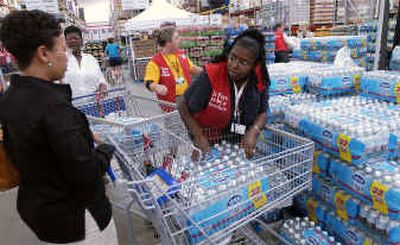 
Sam's Club sales associate Vernice Avery, center, loads cases of bottled water into customer Connie Simon's shopping cart Monday in Montgomery, Ala. 
 (Associated Press / The Spokesman-Review)