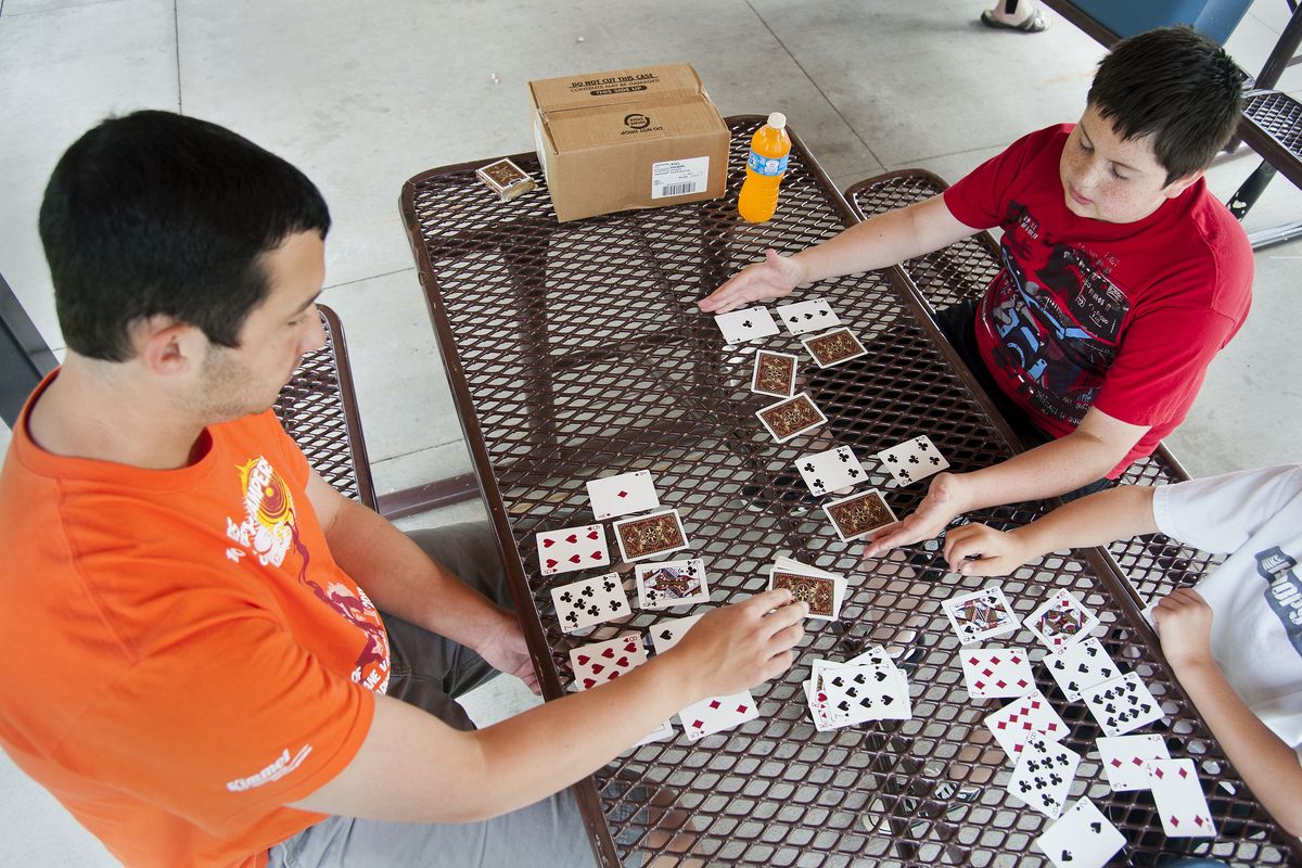 Jordan Minnihan, 13, takes part in a card game Wednesday with Glen Reser, park program leader, left, at Terrace View Park. (Dan Pelle)