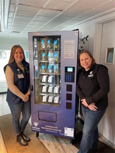Panhandle Health District staff members Katie Schmeer, right, and Makenna Hunziker stand by the newly installed naloxone vending machine at St. Vincent de Paul in Coeur d’Alene.  (Provided by the Idaho Panhandle Health District)