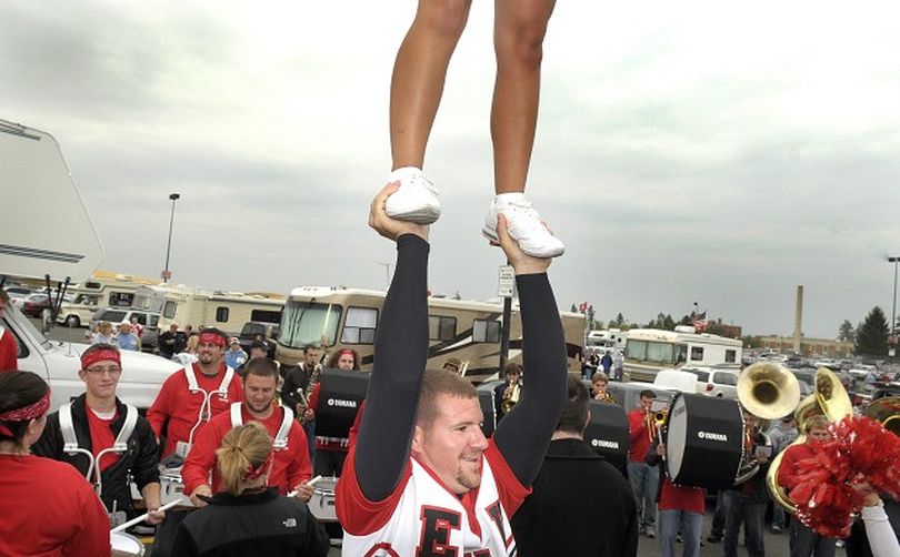 Darin DeBolt holds a fellow cheerleader in a lift as the EWU band rallies fans outside  Woodward Field in Cheney before EWU played Western Washington Sept. 20. (Christopher Anderson / The Spokesman-Review)