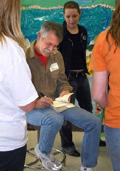 
Chris Crutcher signs a Salk Middle School student's book during the reward con for students who met their Accelerated Reading Program goals. 
 (Kandis Carper / The Spokesman-Review)