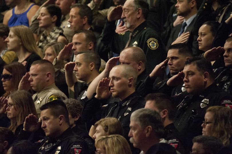 Officers salute during the funeral service for Sgt. Greg Moore at Lake City High School this morning ... (Kathy Plonka)