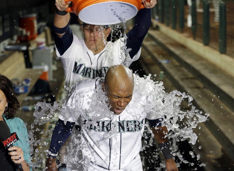 Seattle Mariners' Austin Jackson is hit with a bucket of water by teammate Logan Morrison as Jackson is interviewed after hitting in the winning run against the Baltimore Orioles in the 10th inning of a baseball game Tuesday. The Mariners won 6-5. (Associated Press)