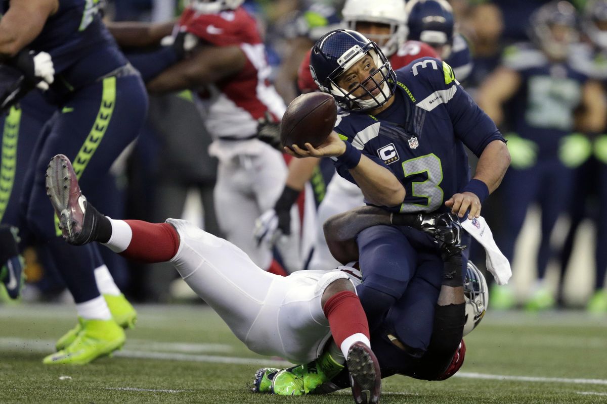 Seahawks quarterback Russell Wilson  is tackled by the  Cardinals’ Sio Moore  in the second half of Cards’ 34-31 win over Hawks. (John Froschauer / Associated Press)