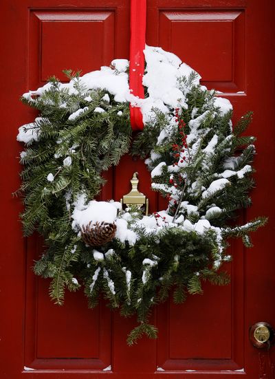 There’s nothing like a forest-y wreath, above, following a winter storm in Philadelphia. Right: This wreath is studded with white felt balls that look like snowballs. It’s available in green or red, too. (Associated Press)