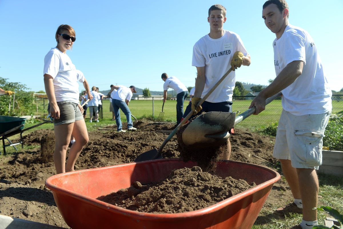 From left, Kate Burke, Connor Otheim and Josh Allan load a wheelbarrow to move soil at the Northeast Community Center garden on Sept. 12, as part of the United Way Day of Action, a volunteer effort by local businesses and service groups. (Jesse Tinsley)
