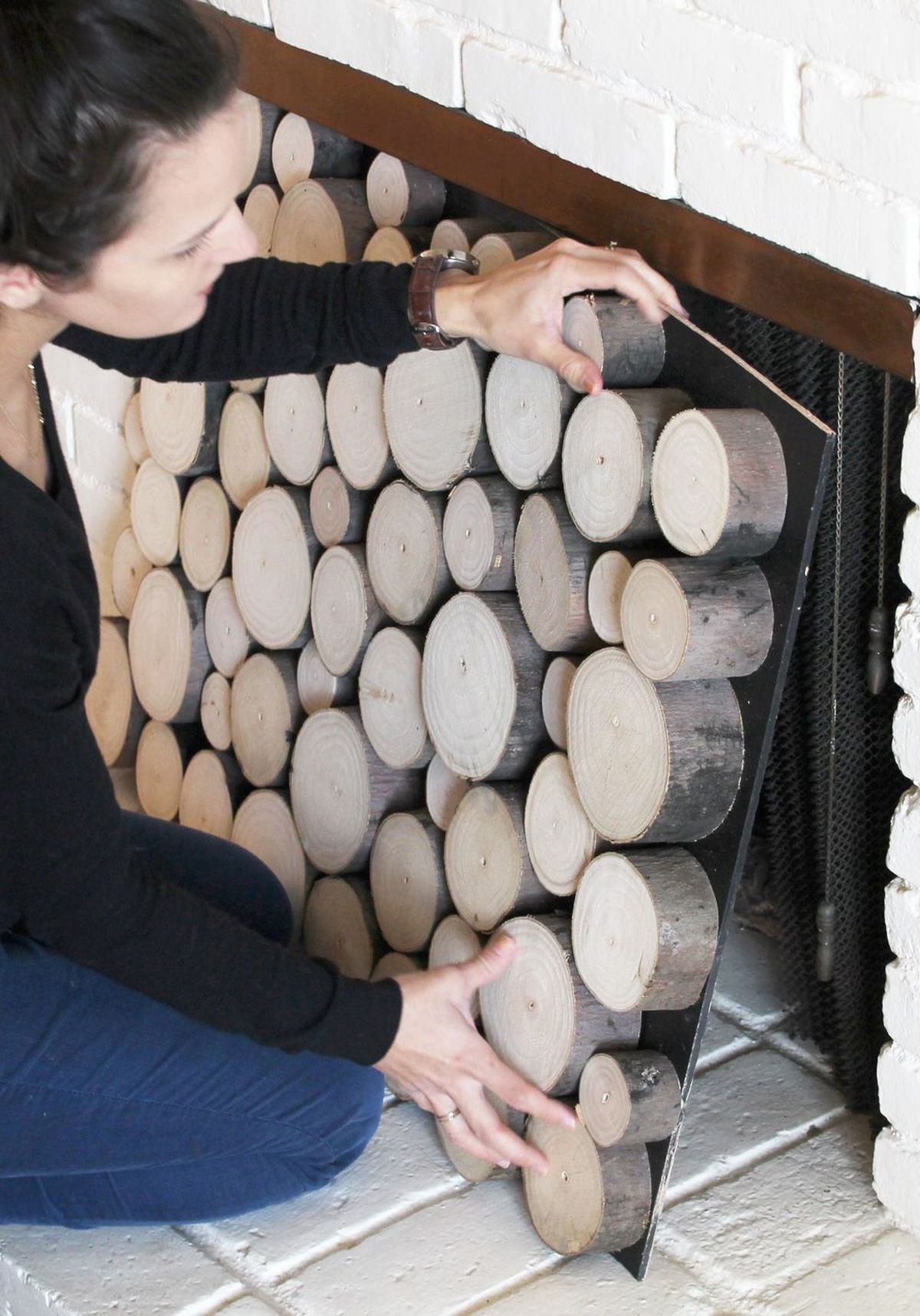 Thin plywood, leftover chalkboard paint, log rounds and glue are what Morgan Spenla used to create her faux log stack facade. To keep everything secure, she nailed each round to the board from the backside.  (Morgan Spenla)