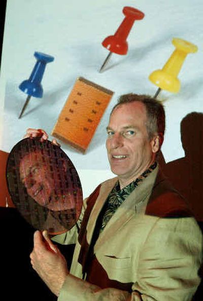 
Jim Kahle, IBM Director of Technology for Cell Technology, holds up a silicon wafer of hundreds of new cell technology chips during a news conference in San Francisco on Monday. In background is an enlarged photo of the new Cell Technology with push pins next to it for scale. 
 (Associated Press / The Spokesman-Review)