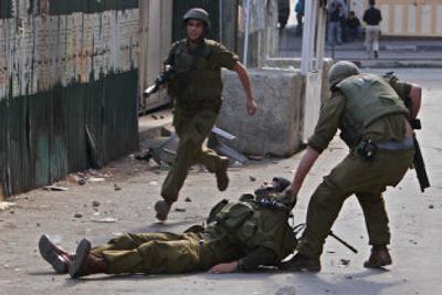 
An Israeli soldier drags another after he was injured by a stone Wednesday in the West Bank town of Hebron during clashes that erupted after a demonstration against the Israeli offensive in Gaza. 
 (Associated Press / The Spokesman-Review)
