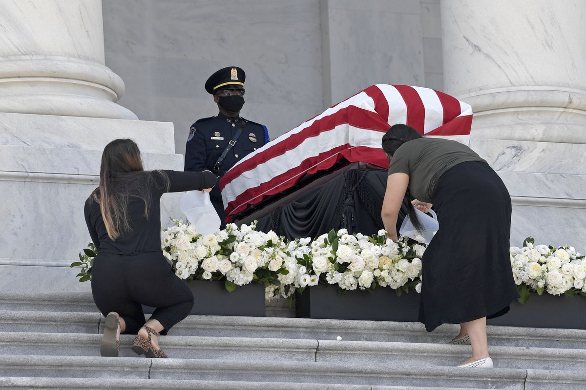 Two women water the flowers near the flag-draped casket of the late Rep. John Lewis, D-Ga., as he lies in state at the top of the East front steps of Capitol Hill in Washington, Tuesday, July 28, 2020.  (Susan Walsh)