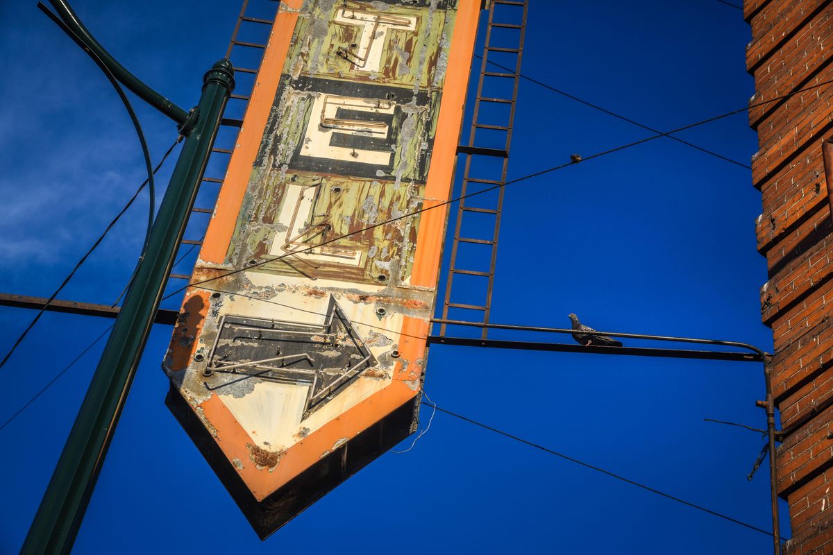 A pigeon heads for home inside the Otis Hotel sign, Wednesday June 20, 2018, as the evening light bathes the west end of downtown Spokane. (Dan Pelle / The Spokesman-Review)